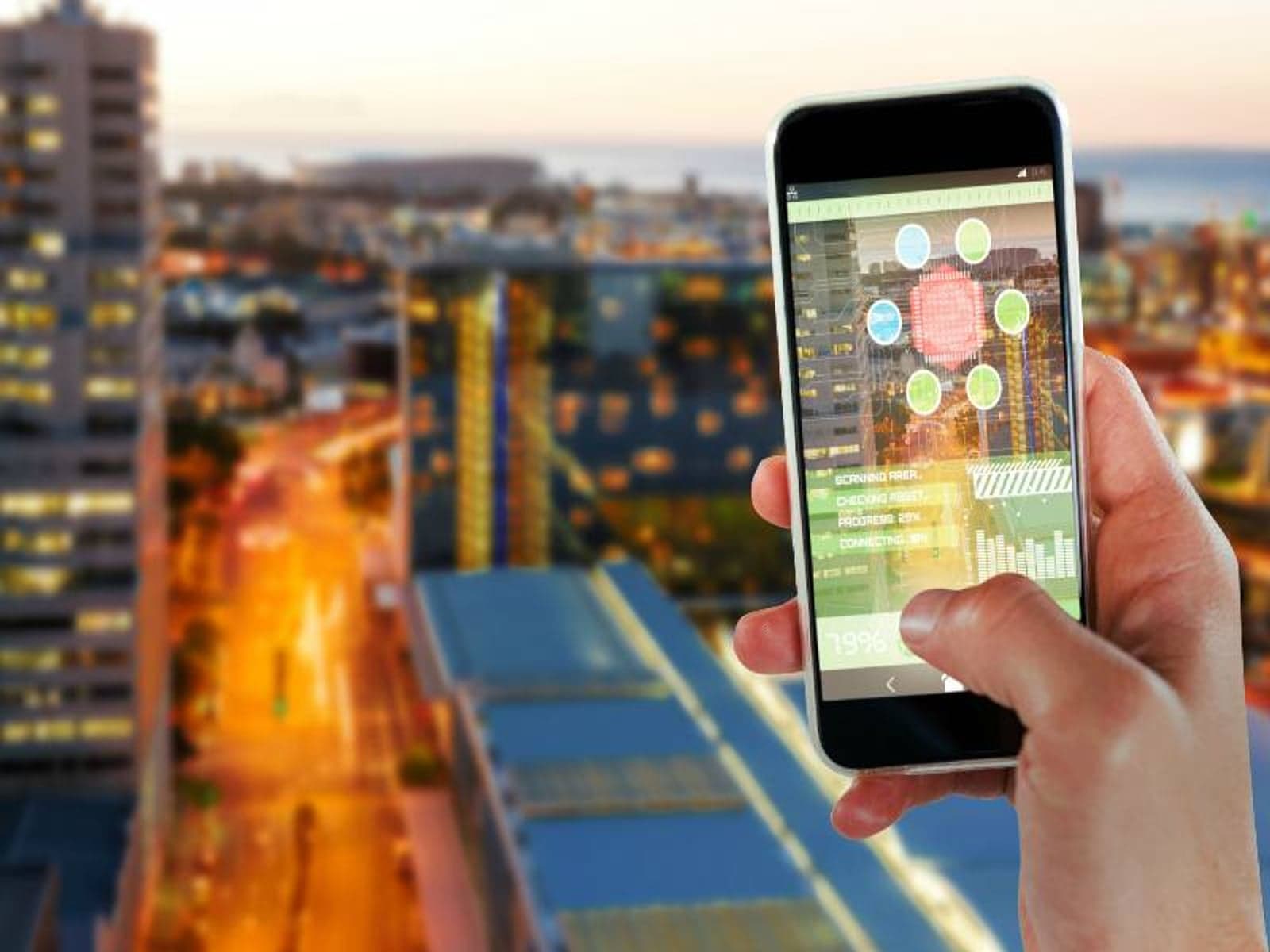 Cropped image of hand holding 3D smart phone against illuminated buildings by road in city