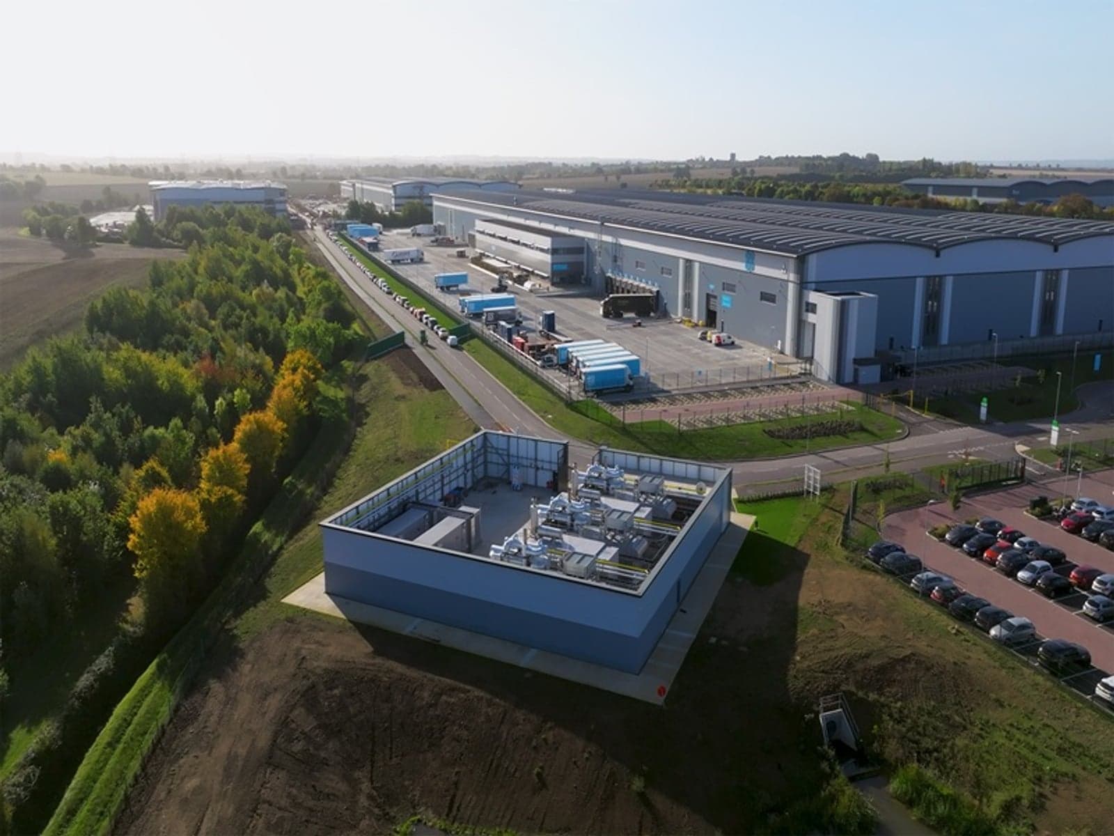 A new energy center will provide customers at the Tritax Symmetry Logistics Park in Biggleswade/UK with reliable, environmentally friendly and cost-effective electricity and heat. The mtu microgrid will also support the public power grid with renewable and stable energy from various sources, including rooftop solar, batteries and a combined heat and power plant.
Ein neues Energiezentrum wird den Kunden im Tritax Symmetrie Logistik-Park in Biggleswade/ UK zuverlässige, umweltfreundliche und kostengünstige Strom- und Wärmeversorgung bieten. Das mtu-Microgrid wird auch das öffentliche Stromnetz mit erneuerbarer und stabiler Energie aus verschiedenen Quellen unterstützen, darunter Solaranlagen auf Dächern, Batterien und eine Kraft-Wärme-Kopplungsanlage.
